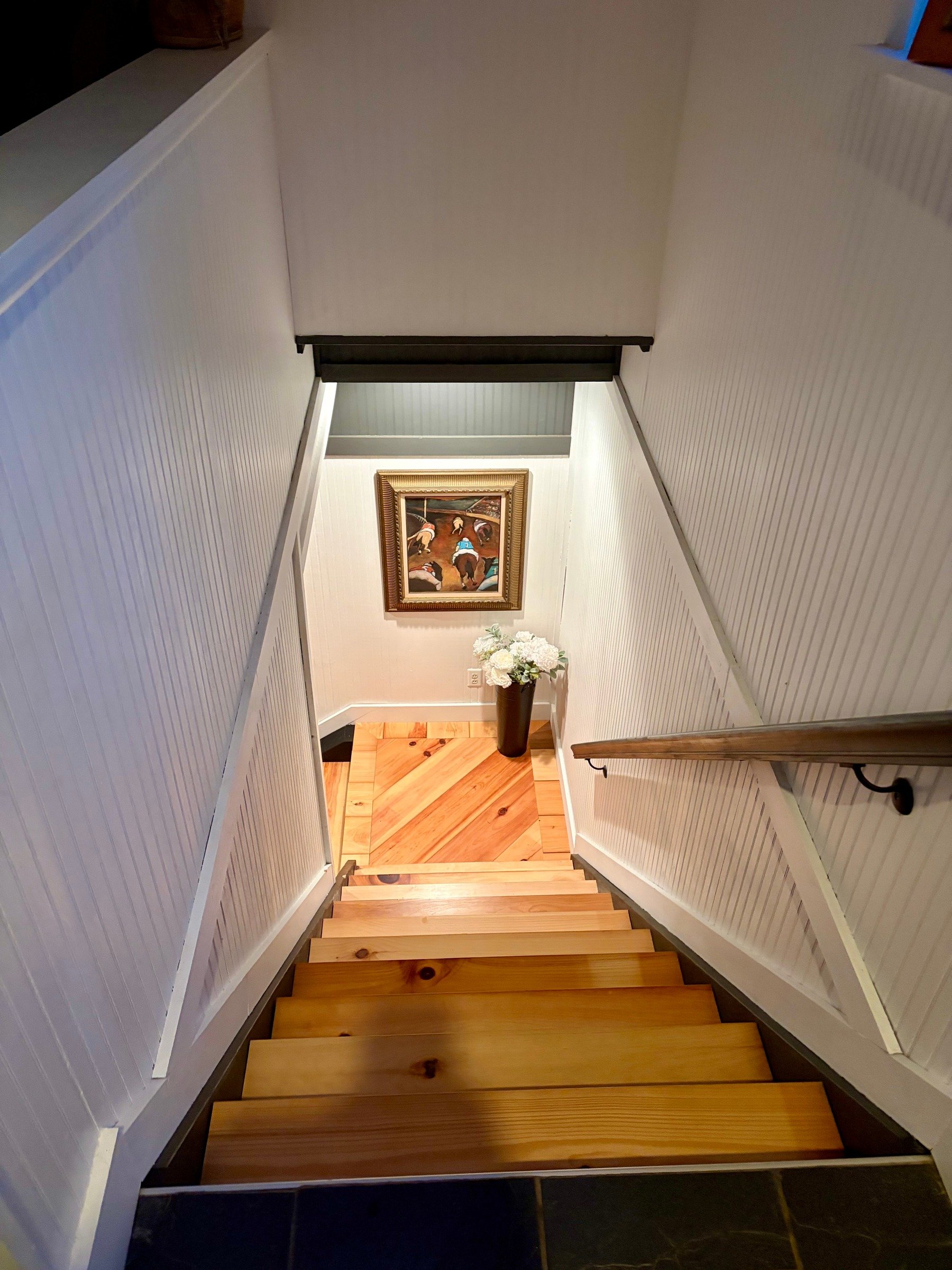 Finished wood stair treads leading to a diagonal-pattern wood landing